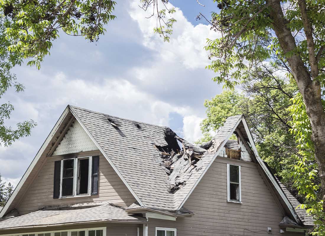 Difference in Conditions Insurance - Close-up of the Roof of a House That Has Collapsed under Blue Sky with Clouds on a Sunny Day